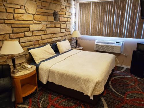 a bedroom with a bed and a brick wall at Jefferson Hills Motel in Clairton