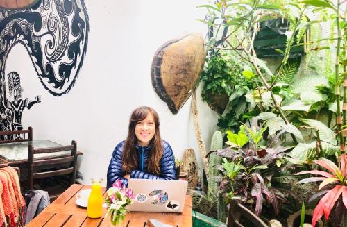 a woman sitting at a table with a laptop at Surf hostel My Friends in Huanchaco