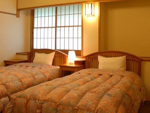 a bedroom with two beds and a window at Yamabiko Ryokan in Minamioguni
