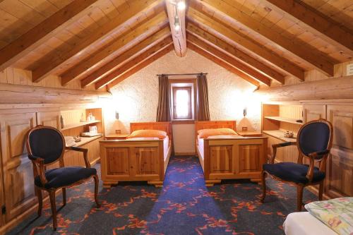 a bedroom with two beds and two chairs in a room at Baita Luleta in Livigno