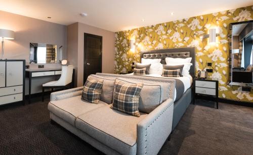 a bedroom with a bed and a couch and a bathroom at Fonab Castle Hotel in Pitlochry