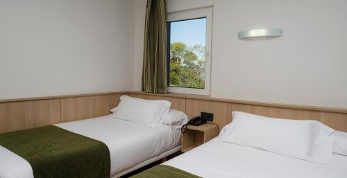 two beds in a room with a window at Hotel Crisol de las Rías in Miño
