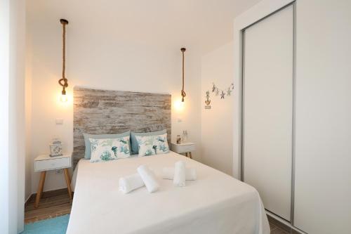 a bedroom with a large white bed with blue pillows at Sea & Sun Apartment II in Nazaré