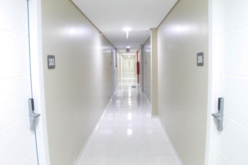 a long hallway with white walls and white tile floors at AJ Hotel Chapecó - Fácil Acesso Pátio Shopping e Rótula da Bandeira in Chapecó