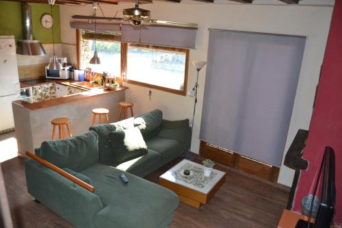 a living room with a green couch and a kitchen at Casa JUNIA in La Baronia de Sant Oisme