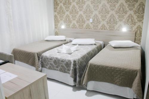 a room with three beds and a table at AJ Hotel Chapecó - Fácil Acesso Pátio Shopping e Rótula da Bandeira in Chapecó