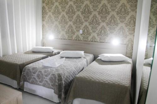 two beds in a small room with wallpaper at AJ Hotel Chapecó - Fácil Acesso Pátio Shopping e Rótula da Bandeira in Chapecó