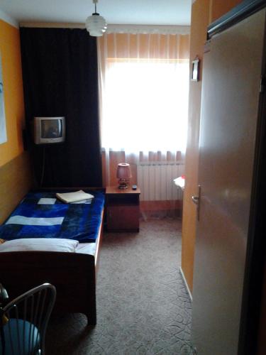 a small bedroom with a bed and a window at Hotel Skarpa in Sejny