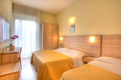 a hotel room with two beds and a window at Hotel Rosso Blu in Cesenatico