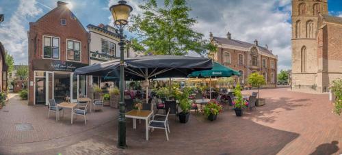 a street with tables and chairs under an umbrella at Hart van Lochem in Lochem