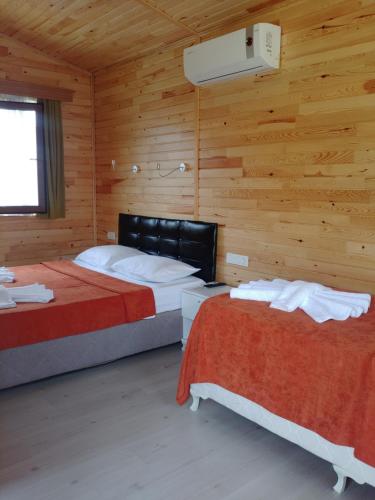 two beds in a room with wooden walls at Villa Efsane Hotel in Cıralı