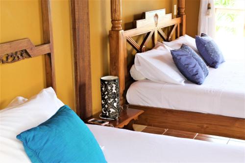 a bedroom with two beds with blue and white pillows at Luxury Suites Vila Indonésia in Garopaba