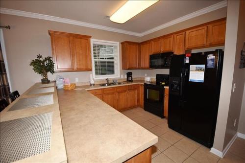 a kitchen with wooden cabinets and a black refrigerator at 1515 Willow Bend Condo in North Myrtle Beach
