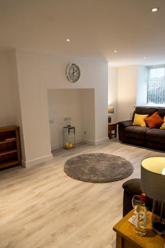 a living room with a couch and a clock on the wall at Sandy bottoms in Llandudno