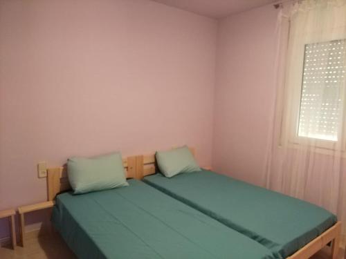 Schlafzimmer mit einem Bett mit grüner Bettwäsche und einem Fenster in der Unterkunft Cal Bover in Olot