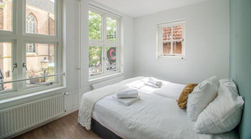 a white bedroom with a bed and two windows at Hart van Lochem in Lochem