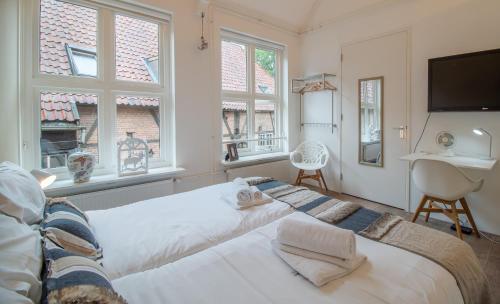 a bedroom with a large bed and two windows at Hart van Lochem in Lochem