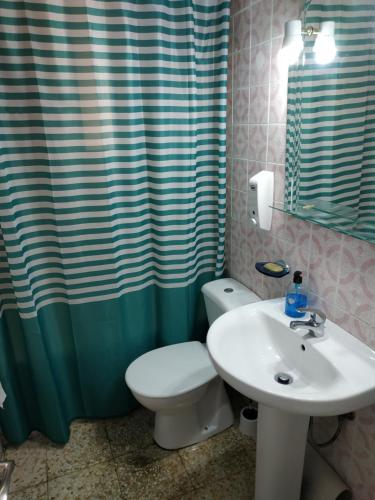 a bathroom with a toilet and a sink and a shower curtain at Habitación en piso particular 4 min.aeropuerto in Seville