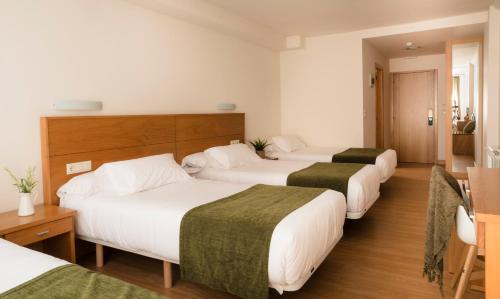 a hotel room with four beds in a row at Hotel Crisol de las Rías in Miño