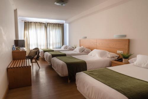 a row of four beds in a hotel room at Hotel Crisol de las Rías in Miño