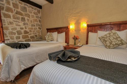 a bedroom with two beds and a stone wall at Hotel San Marcos in San Cristóbal de Las Casas