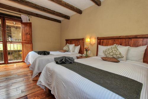 a bedroom with two beds with white sheets at Hotel San Marcos in San Cristóbal de Las Casas