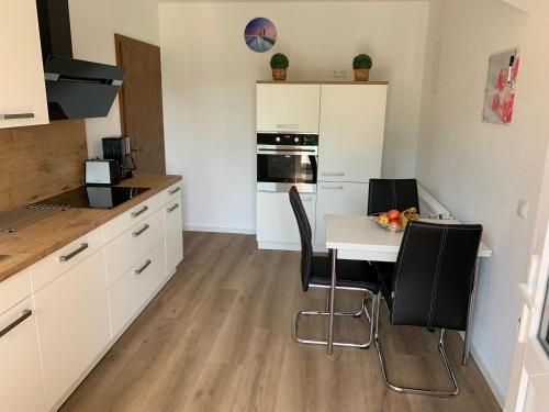 a kitchen with white cabinets and a table and chairs at Ferienwohnung nahe Bentheimer Wald in Schüttorf
