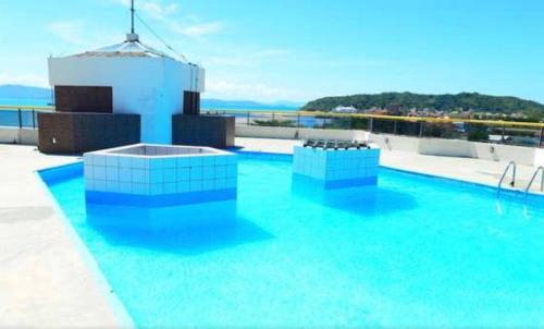 a swimming pool on top of a building with blue water at Apartamento beira mar em Ponta das Canas in Florianópolis