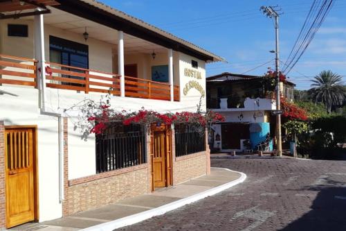 a white house with red flowers on the balcony at Hospedaje Germania in Puerto Ayora