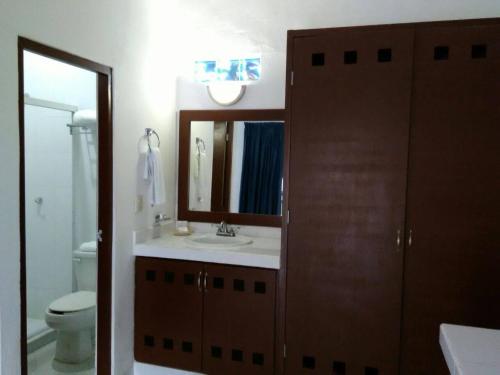 a bathroom with a sink and a toilet and a mirror at Hotel Plaza Almendros in Isla Mujeres