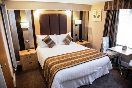 a hotel room with a large bed and a desk at Trivelles Park Hotel in Preston