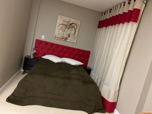 a bedroom with a bed with a red headboard at Hotel Brasilia Curitiba in Curitiba