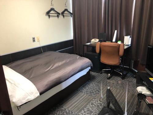a bedroom with a bed and a desk with a computer at Business Stay in Satsumasendai