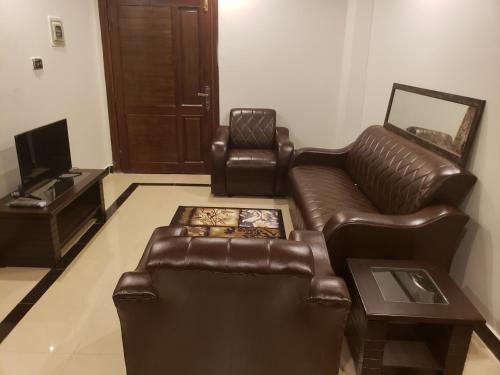 a living room with a leather couch and a chair at Rove Lodging-One Bed Apartment,Bahria Town in Rawalpindi