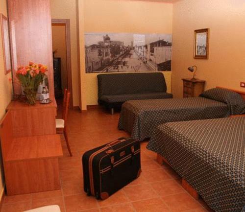 une chambre d'hôtel avec deux lits et une valise dans l'établissement Albergo Corte Antica, à Villafranca di Verona