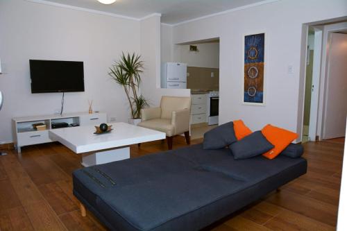 sala de estar con sofá, mesa y TV en Petit Apart Villa Regina en Villa Regina