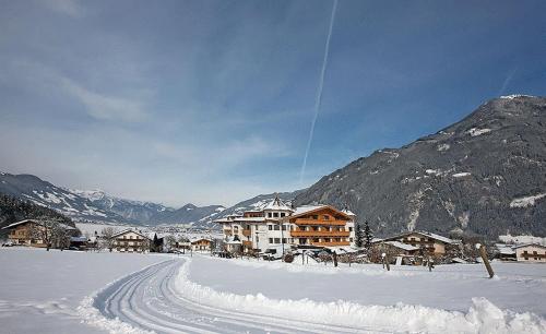 a snow covered street with houses and a mountain at Hotel Magdalena im Zillertal - Urlaub mit Hund in Ried im Zillertal