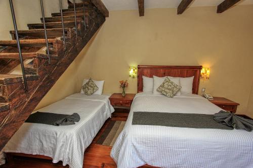 two beds in a room with a staircase at Hotel San Marcos in San Cristóbal de Las Casas