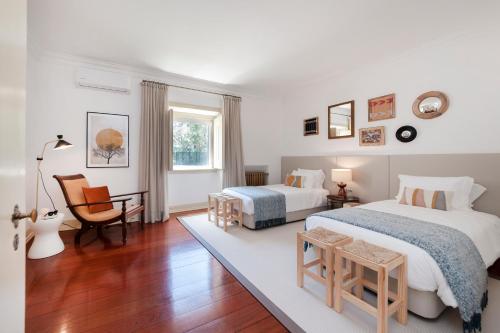 a bedroom with two beds and a chair at Quinta da Arrábida in Sesimbra