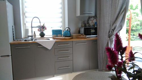 a kitchen with white cabinets and a sink and a window at Willa nad Sołą guest house in Oświęcim