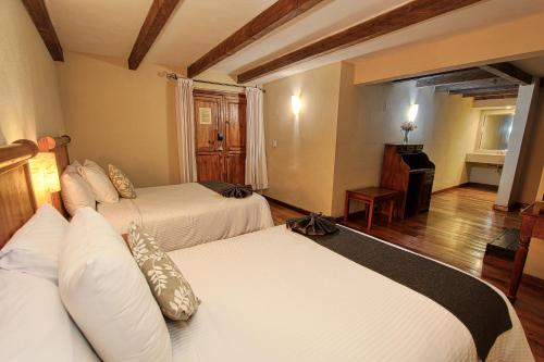 a hotel room with two beds and a piano at Hotel San Marcos in San Cristóbal de Las Casas