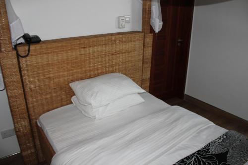 Bett mit weißer Bettwäsche und Kissen in einem Zimmer in der Unterkunft Villa Dahl Beach Resort in Daressalam
