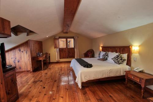 a bedroom with a large bed and wooden floors at Hotel San Marcos in San Cristóbal de Las Casas