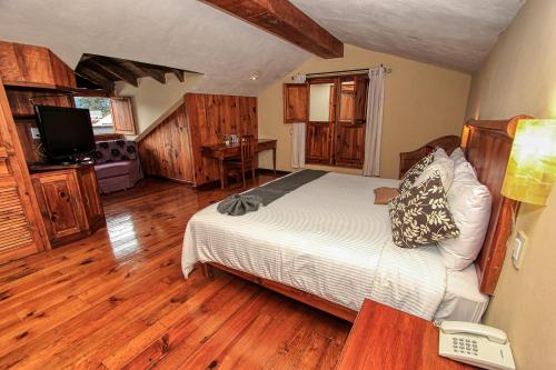 a bedroom with a bed and a television and wooden floors at Hotel San Marcos in San Cristóbal de Las Casas