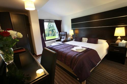 a hotel room with a large bed and a table at Ewenny Farm Guest House in Bridgend