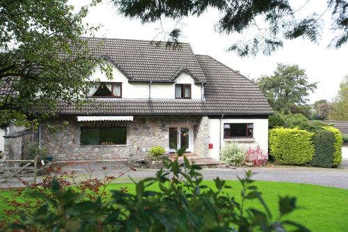 a white house with a black roof at Ewenny Farm Guest House in Bridgend
