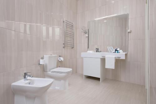 a white bathroom with a toilet and a sink at Hotel Orlinye Skaly in Pyatigorsk