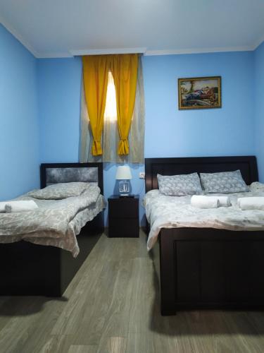 - une chambre avec 2 lits et un mur bleu dans l'établissement Apartment LINIMA, à Tbilissi