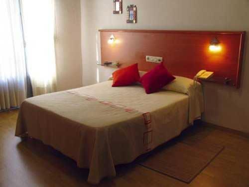 um quarto com uma cama grande e almofadas vermelhas em Hotel Casablanca Vigo em Vigo