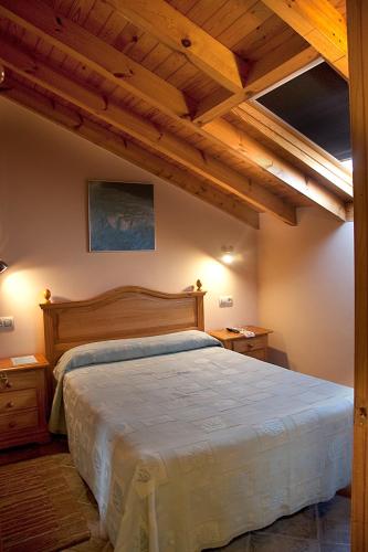 a bedroom with a large bed with wooden ceilings at Apartamentos Cuevas del Mar in Nueva de Llanes